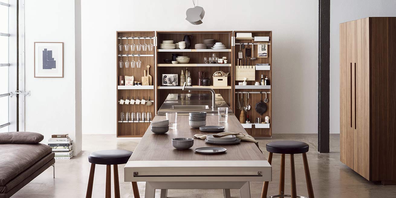 Cuisine-atelier bulthaup b2 : armoires ouvertes en noyer, établi central inox et tabourets