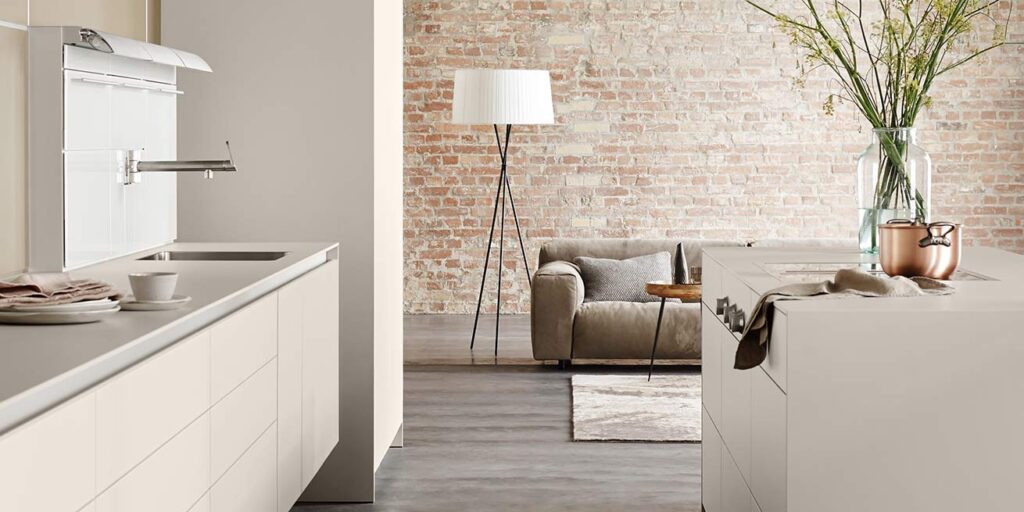 Cuisine bulthaup b3 beige ouverte sur le séjour, îlot et canapé, une cuisine pensée pour recevoir dans un appartement parisien