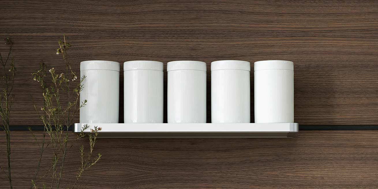 Pots de conservation en porcelaine sur tablette aluminium, panneau mural bulthaup en noyer : l'office prêt à recevoir